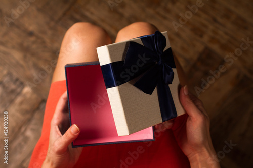  Woman opening a cardboard gift box with blue ribbon photo