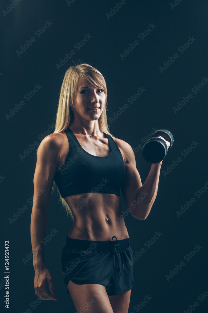 Athletic woman with dumbbells on a dark background Athletic woman with dumbbells on a dark background