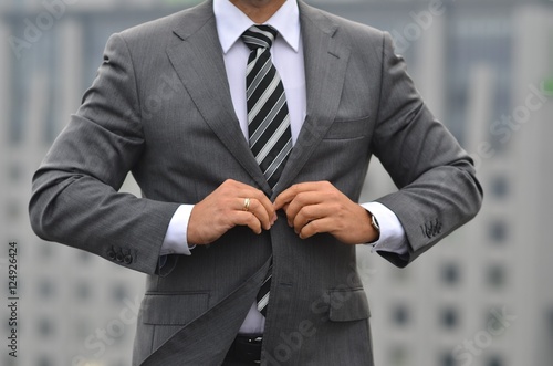 Handsome young businessman in classic suit is buttoning his jacket