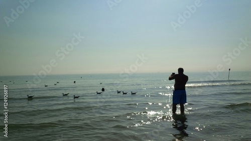 uomo che fotografa i gabbiani in mare