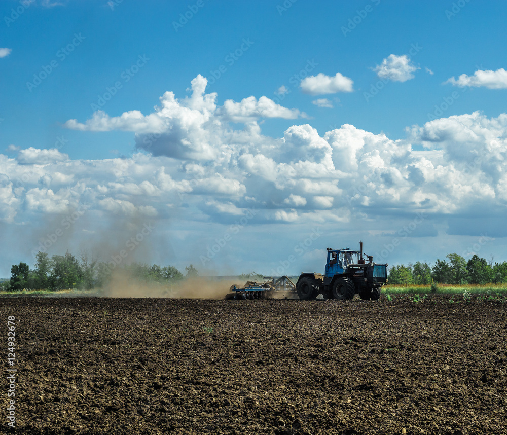 Fototapeta premium Agricultural Landscape - Tractor working on the field - spring sunny day