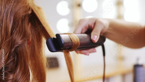 Hairdresser curling hair to foxy girl in beauty salon Close up Slow motion