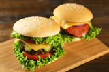 Big tasty hamburgers on wooden board