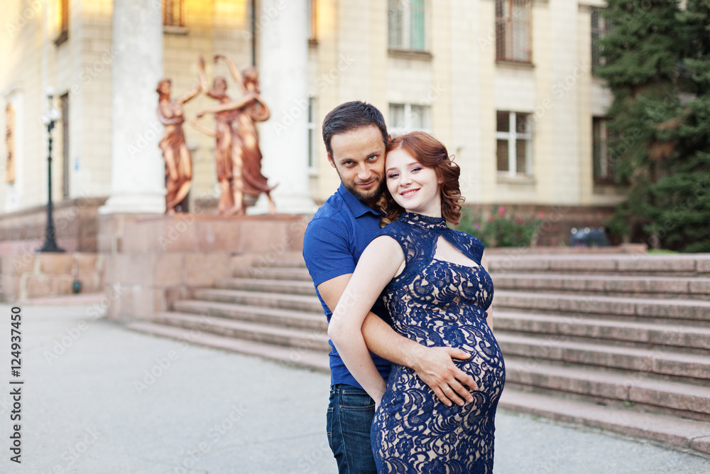 Pregnant red hair woman in long blue dress and stylish man 