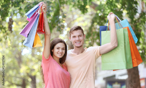 Happy couple with colorful shopping bags in park