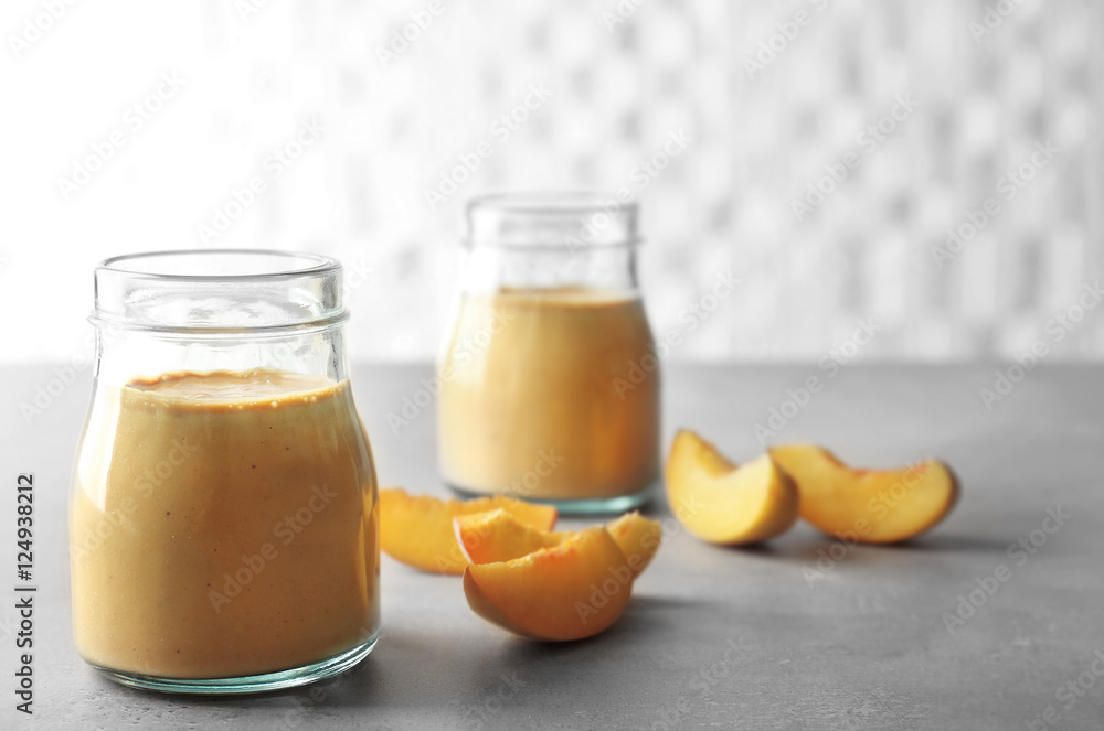 Mason jars with tasty smoothie and peach on table Mason jars with tasty smoothie and peach on table