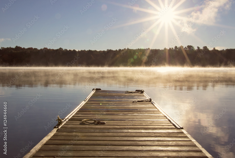 Cottage Dock  over looking the clam lake water on a misty morning with the sun shine