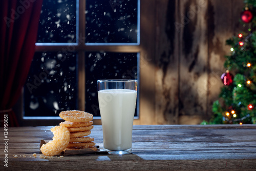 close up view of glass of milk with cookies on color back photo