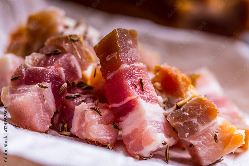 Raw smoked bacon slices on wooden board with cumin and herbs. Raw smoked bacon slices on wooden board with cumin and herbs.