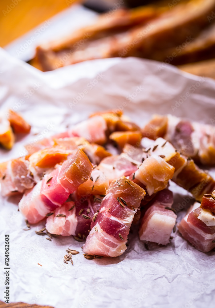 Raw smoked bacon slices on wooden board with cumin and herbs. Raw smoked bacon slices on wooden board with cumin and herbs.