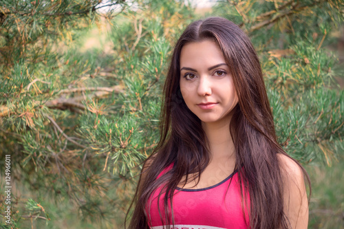 Young beautiful brunette model posing in the sports image of the park against the backdrop trees © Oleksandr Masnyi