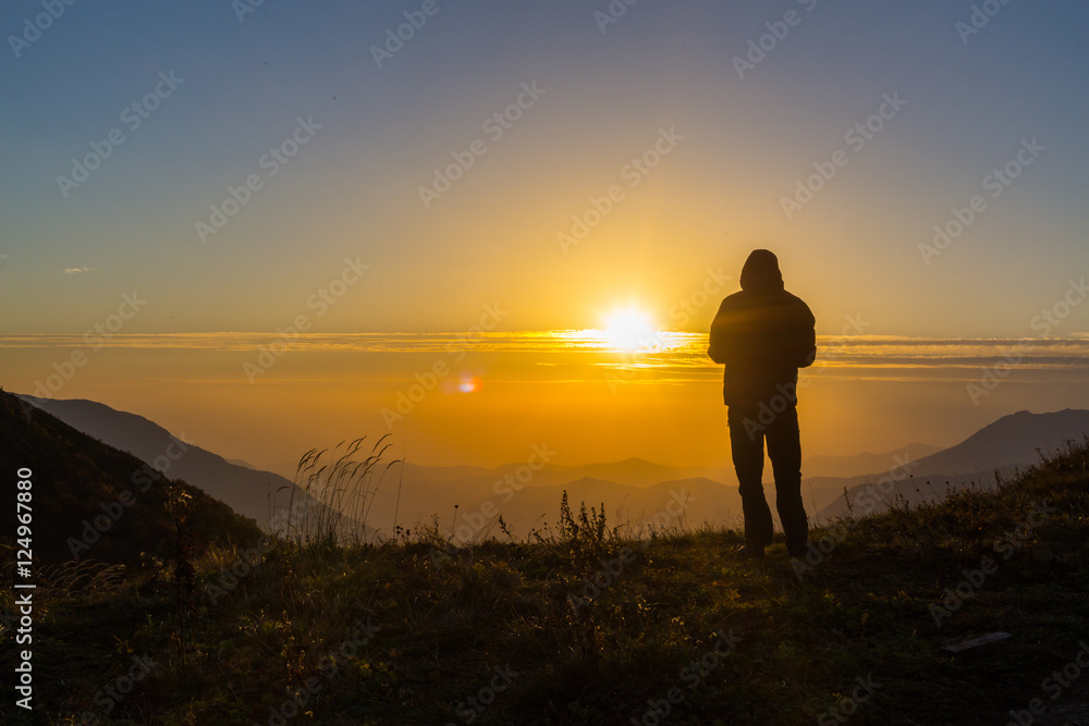 Silhouette of one young man standing at the mountains top