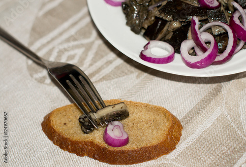 Маринованные грибы с луком и хлебом на тарелке, вилка