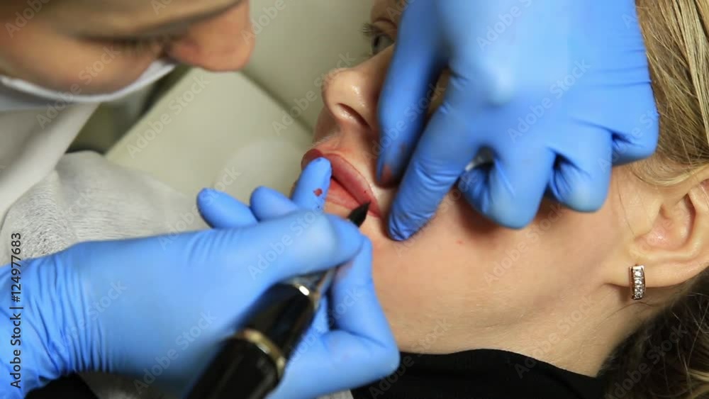 Cosmetologist applying permanent make-up. Young beautiful woman having cosmetic tattoo on her lips. Healthy Spa Cosmetologist applying permanent make-up. Young beautiful woman having cosmetic tattoo on her lips. Healthy Spa