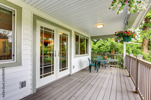 Large covered porch with railings and outdoor seats