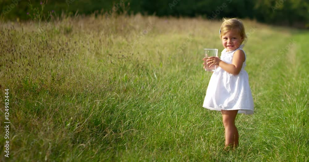 adorable little girl of two years immersed in nature in spring and drink water adorable little girl of two years immersed in nature in spring and drink water