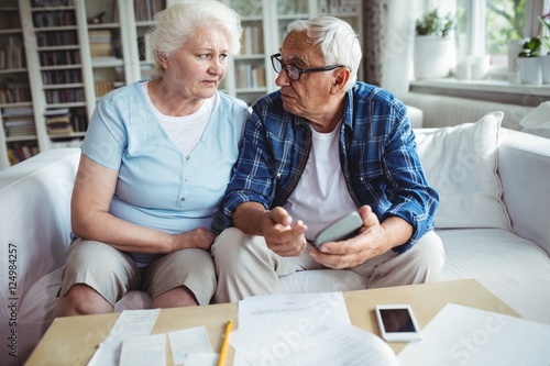 Worried senior couple interacting while checking the bills