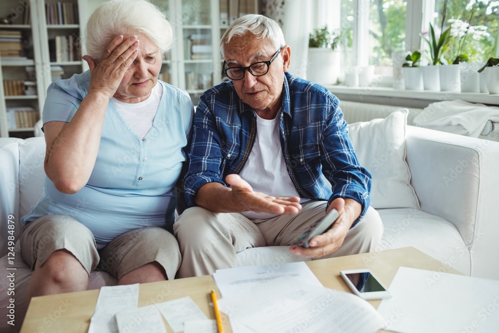 Worried senior couple interacting while checking the bills Worried senior couple interacting while checking the bills