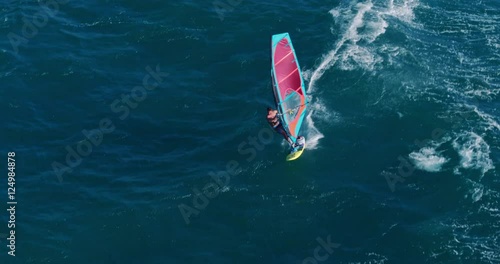 Aerial view of windsurfer gliding across blue ocean, extreme sport