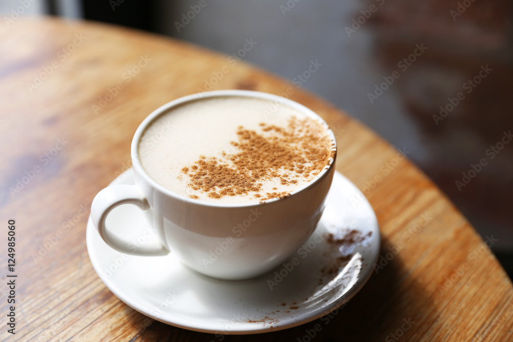 Cup of tasty latte is standing on the wooden textured table with the brick wall background. Latte is in the white big cup. Cup of tasty latte is standing on the wooden textured table with the brick wall background. Latte is in the white big cup.