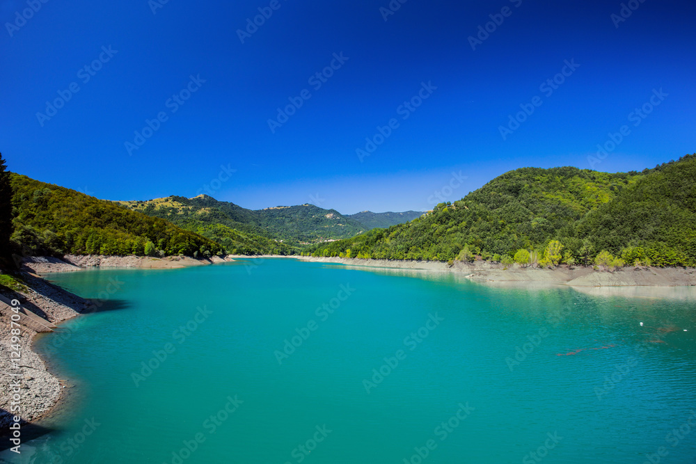 The mountain lake with green water under a blue clear sky The mountain lake with green water under a blue clear sky