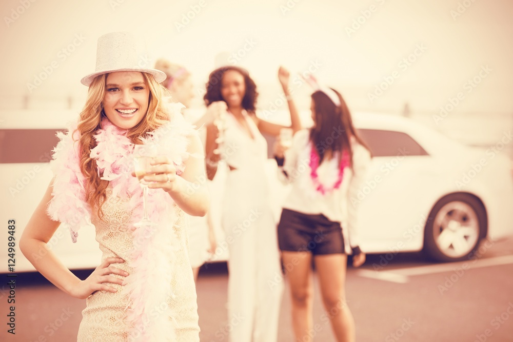 Women holding champagne next to limousine