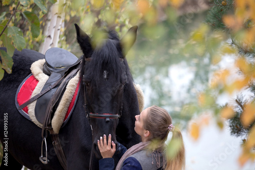 girl with a black horse in the autumn under birch © makam1969