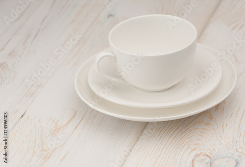 one white cup and saucer on old wooden board