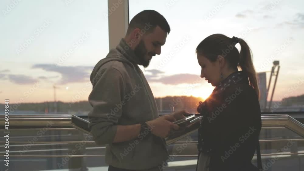 A young couple using a tablet at sunset. A young couple using a tablet at sunset.