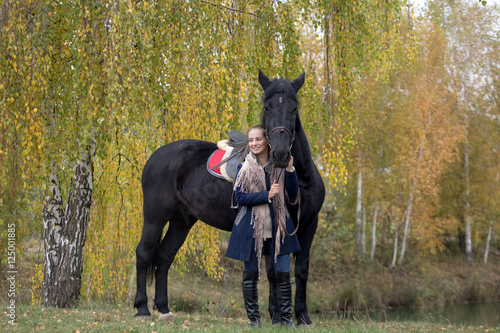 girl with a black horse in the autumn under birch © makam1969