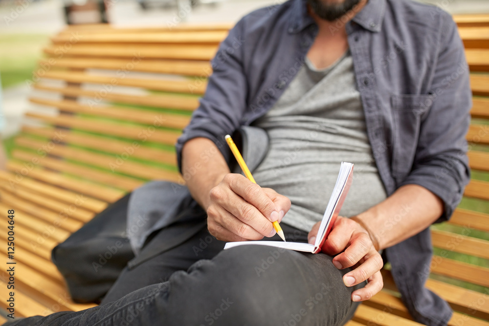 close up of man writing to notebook on city street close up of man writing to notebook on city street