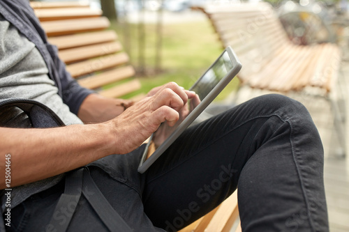 close up of man with tablet pc sitting on bench