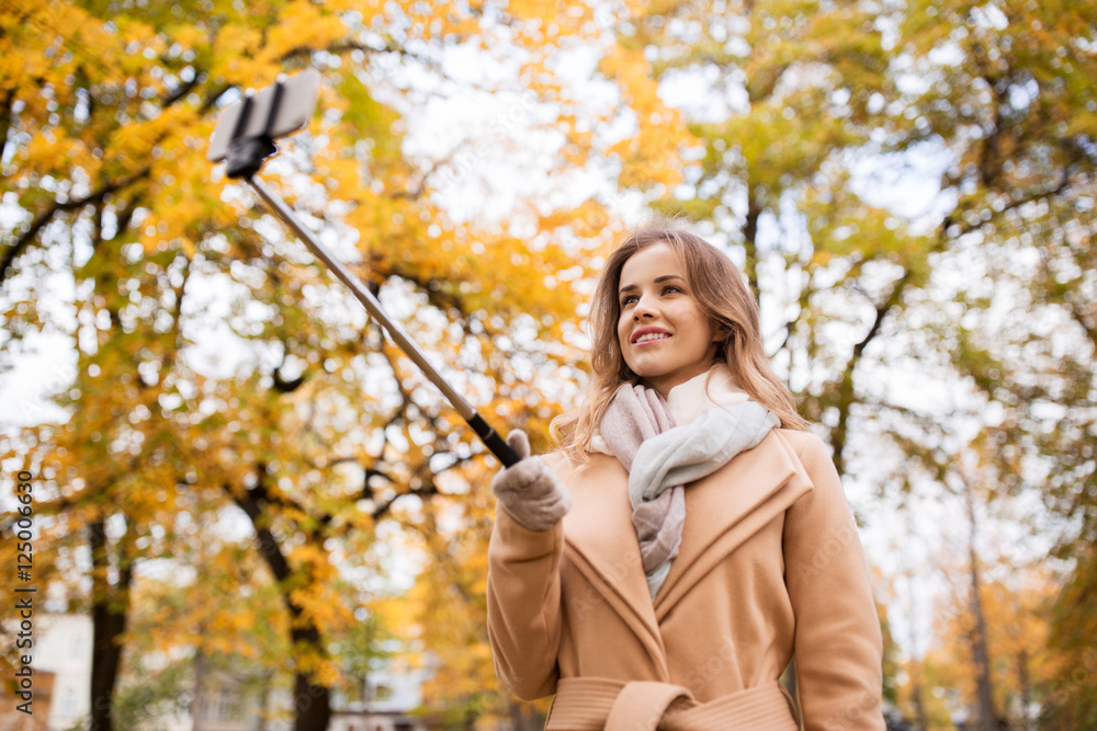 woman taking selfie by smartphone in autumn park woman taking selfie by smartphone in autumn park
