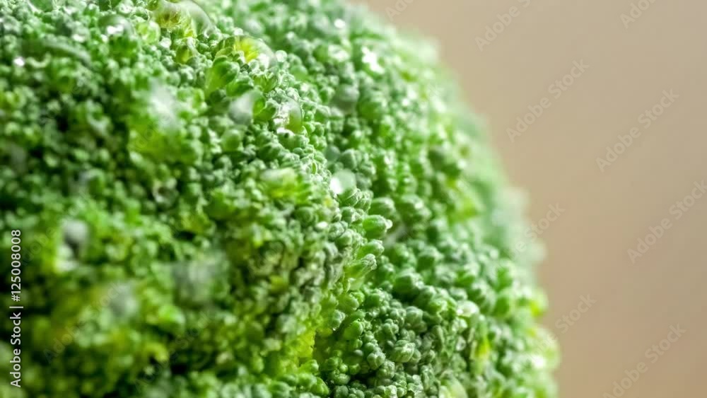 Detailed closeup of water drops spraying and splashing onto raw broccoli florets