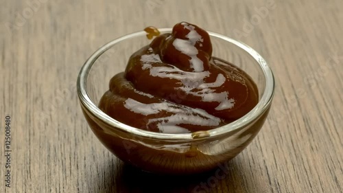 Tasty peppery barbecue sauce quickly filling up bowl amd creating a swirl texture