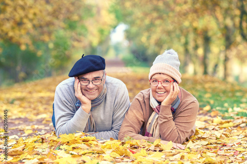 entspanntes Seniorenpaar liegt im bunten Laub - Herbst im Park