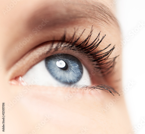 Closeup of human eye with blue pupil and long eyelashes over white background. Eyesight, disease and treatment concept. 