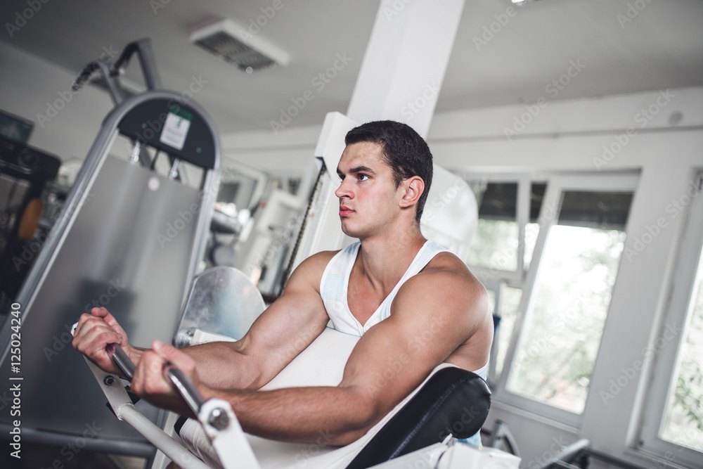 Young attractive adult man exercising and doing weight lifting at fitness gym. Sport training indoors. Young attractive adult man exercising and doing weight lifting at fitness gym. Sport training indoors.