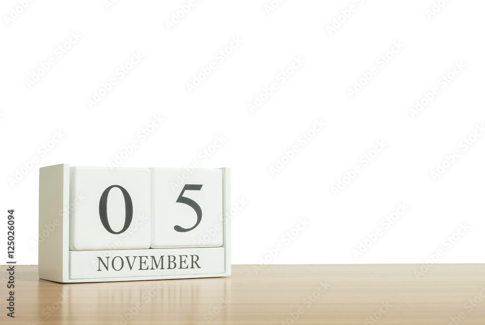 Obraz premium Closeup surface white wooden calendar with black 5 november word on blurred brown wood desk isolated on white background with copy space , selective focus at the calendar