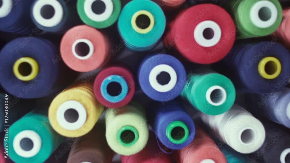 Sewing Threads On Spool. Closeup. Colorful spools of thread in textile factory. Manufacture industrial textile spinning. Textiles and Fabrics. Shot of colorful rolls of woolen. Sewing Threads On Spool. Closeup. Colorful spools of thread in textile factory. Manufacture industrial textile spinning. Textiles and Fabrics. Shot of colorful rolls of woolen.