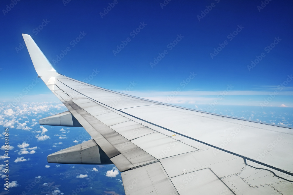 Airliner wing in flight on blue sky background