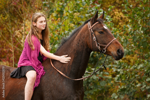Mädchen mit Pferd vor Herbstlaub