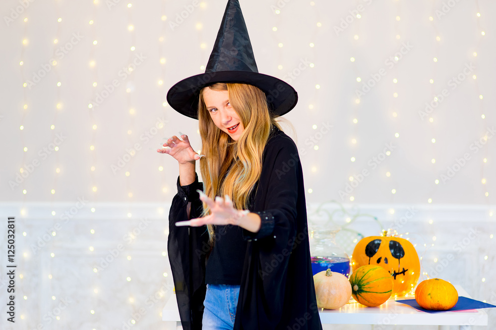 Teenager girl in witch costume posing with pumpkins Teenager girl in witch costume posing with pumpkins