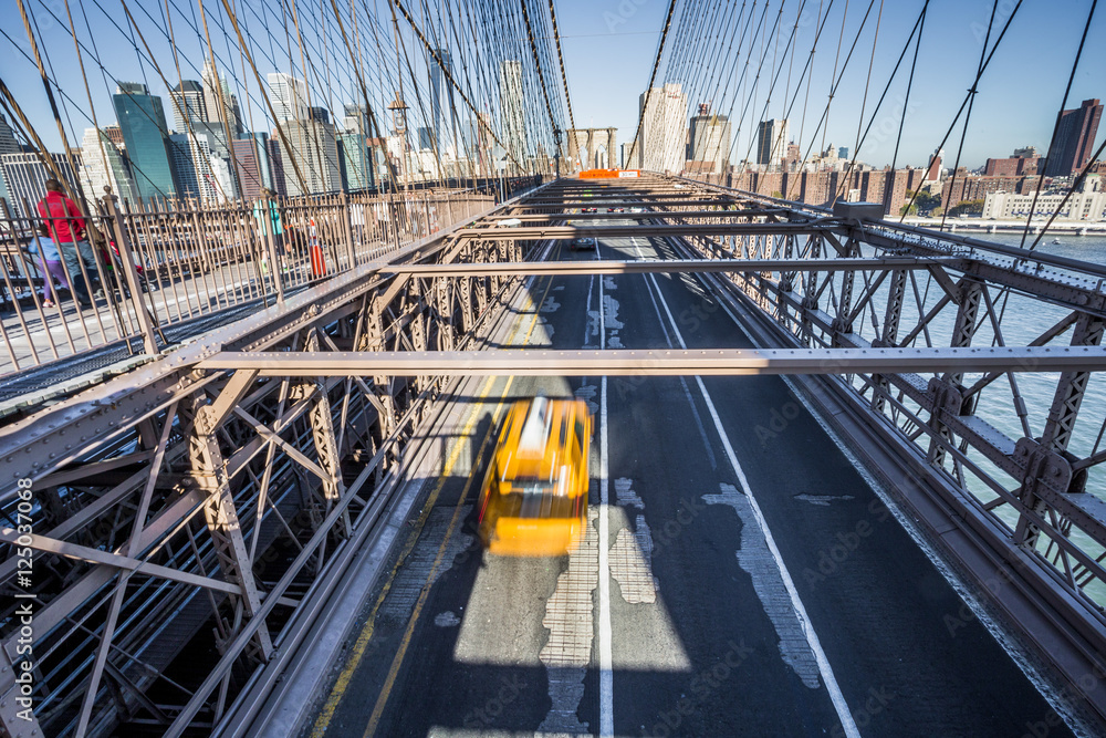 Naklejka premium Taxi taksówka krzyżuje most brooklyńskiego w Nowy Jork, Manhattan linia horyzontu w tle
