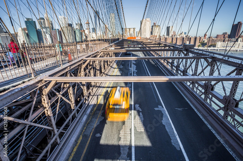Taxi cab crossing the Brooklyn Bridge in New York, Manhattan skyline in background © EyesTravelling