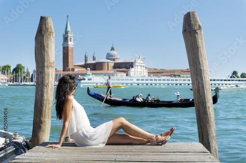 beautiful young tourist woman enjoying the venetian view with gondolas floating in the blue sea © boryanam