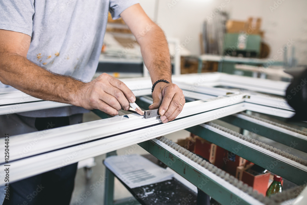 Manual worker assembling PVC doors and windows. Manufacturing jobs. Selective focus. Factory for aluminum and PVC windows and doors production. Manual worker assembling PVC doors and windows. Manufacturing jobs. Selective focus. Factory for aluminum and PVC windows and doors production.