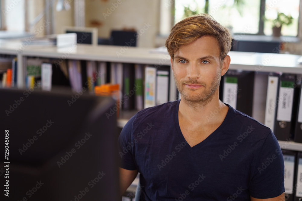 Fototapeta premium mann sitzt am schreibtisch im büro und schaut auf seinen computer
