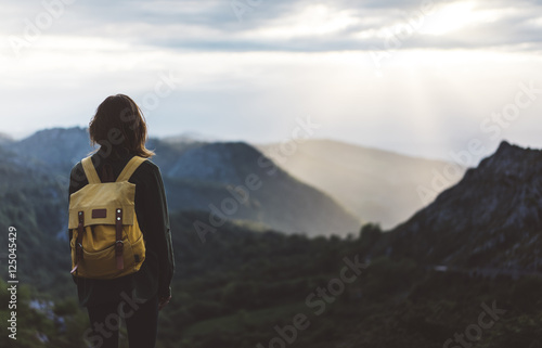 Hipster young girl with bright backpack enjoying sunset on peak of foggy mountain. Tourist traveler on background valley landscape view mockup. Hiker looking sunlight in trip, mock up for text