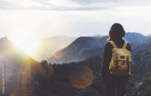 Hipster young girl with bright backpack enjoying sunset on peak of foggy mountain. Tourist traveler on background valley landscape view mockup. Hiker looking sunlight flare in trip Picos de Europa
